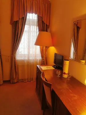 a room with a desk with a lamp and a window at River Star Hotel in Prague