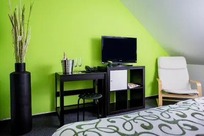 a bedroom with green walls and a desk with a television at Bona Serva in Prague