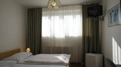 a bedroom with a bed and a window with a television at Pension Filip in Prague