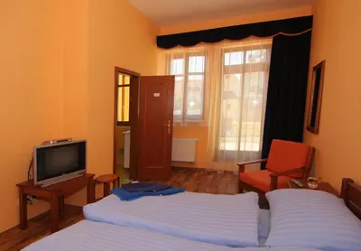 a bedroom with two beds and a tv and a chair at Hotel U Radnice in Louny