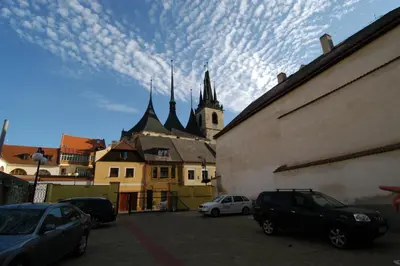 a group of cars parked in a parking lot with a church at Hotel U Radnice in Louny