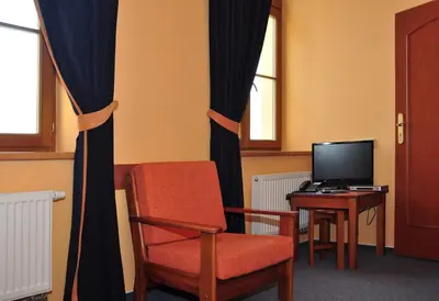 a room with a chair and a desk with a television at Hotel U Radnice in Louny