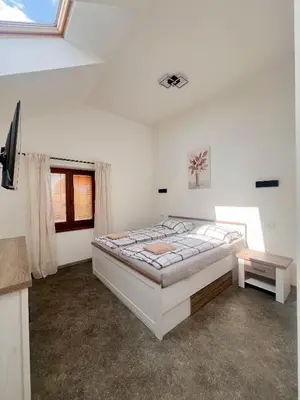 a white bedroom with a bed and a window at Apartmány Pod Řípem in Roudnice nad Labem