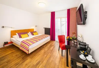 a hotel room with a bed and a red chair at Bellevue Hotel Benešov in Benešov