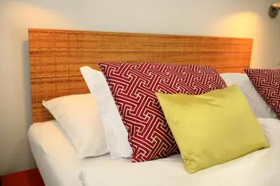 a bed with red and white pillows and a wooden headboard at Bellevue Hotel Benešov in Benešov