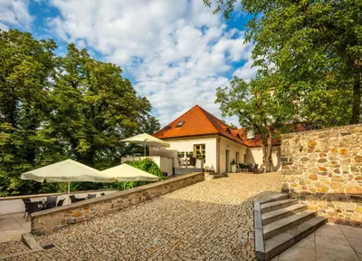 a house with an orange roof and some tables and umbrellas at Bellevue Hotel Benešov in Benešov