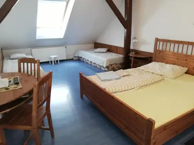 two beds in a room with a table and chairs at Pension U kostela in Český Brod