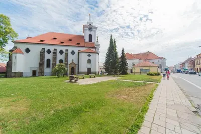 a church with a clock tower on a grass field at Pension U kostela in Český Brod