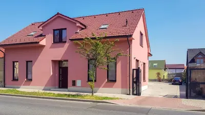 a pink house with a red roof on a street at Apartment De Luna in Prague