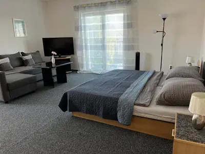 a bedroom with a bed and a couch and a television at Penzion Ariane in Prague