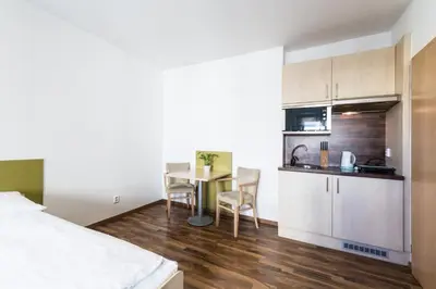 a room with a bed and a table and a kitchen at Penzion Palouček in Prague