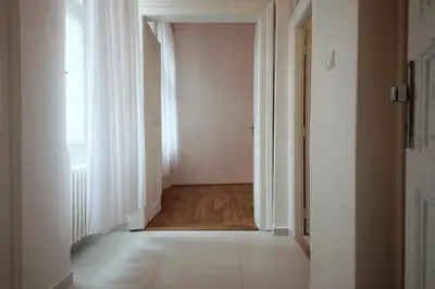 an empty hallway with white doors and a tile floor at Sekaninova 52 Retro Flat in Prague
