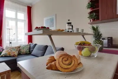 a table with a plate of bread and a bowl of fruit at Prague Siesta Apartments in Prague