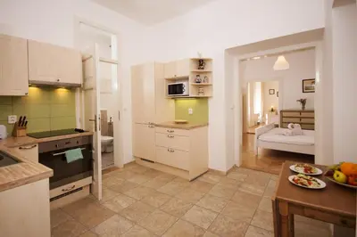 a kitchen with white cabinets and a kitchen with a table at Prague Siesta Apartments in Prague