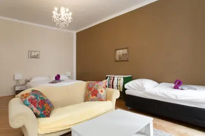 a room with two beds and a couch and a chandelier at Prague Siesta Apartments in Prague