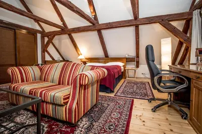 a living room with a couch and a bed at Hotel Dvur Hoffmeister in Velké Číčovice