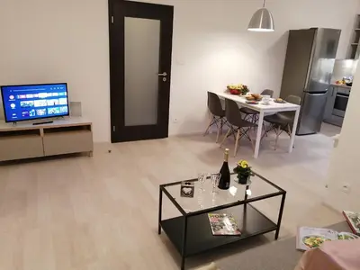a living room with a television and a table with a bottle of wine at Prima Family Apartments in Prague