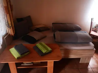 a room with two beds and a wooden table at Green Apartments in Luštěnice