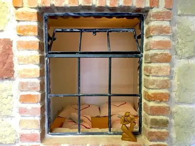 a window in a brick wall with a bed at Green Apartments in Luštěnice