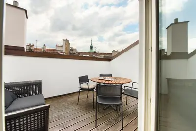 a balcony with a table and chairs and a view of the city at Kolkovna 5 Penthouse in Prague