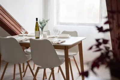 a dining room table with white chairs and a bottle of wine at Prague - Karlin Apartments in Prague
