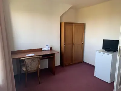 a small room with a desk and a refrigerator at Hotel-Pension KAMÝK in Prague