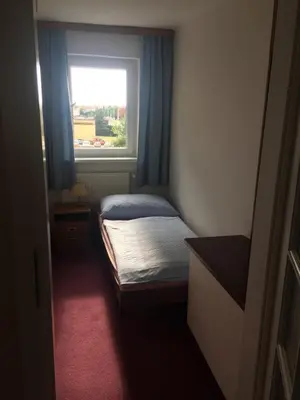 a small bedroom with a bed and a window at Hotel-Pension KAMÝK in Prague