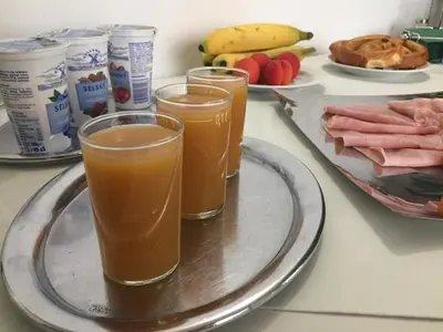three glasses of orange juice on a tray with food at Hotel-Pension KAMÝK in Prague