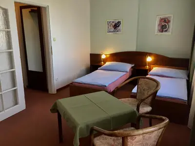 a room with two beds and a table and a chair at Hotel-Pension KAMÝK in Prague