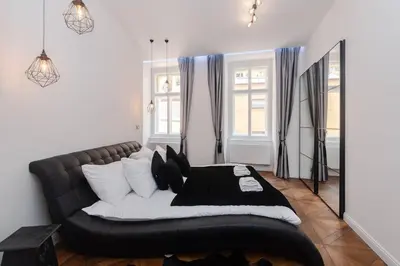 a bedroom with a black leather couch and windows at Arch III at Wenceslas in Prague