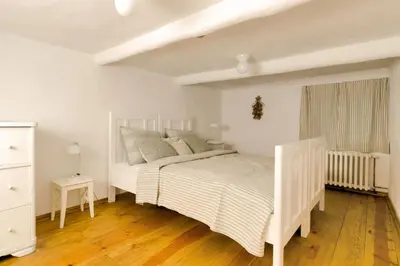 a white bedroom with a bed and a window at Homutův statek in Kokořín