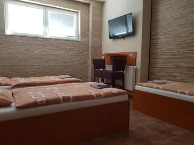 a room with two beds and a flat screen tv at Penzion Hudebka in Louny