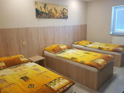 three beds in a room with yellow sheets at Penzion Hudebka in Louny