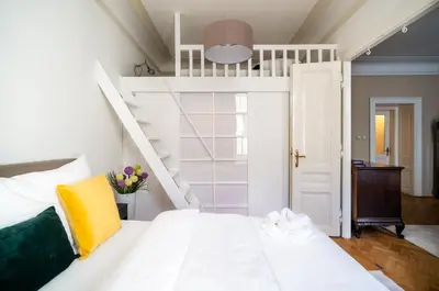 a bedroom with a white bunk bed and a staircase at Luxurious Kafka family apt in Old Town in Prague
