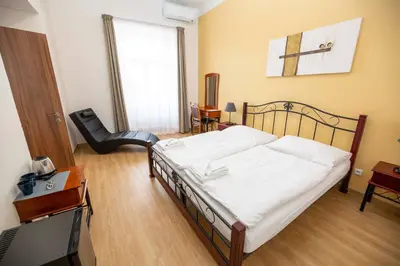 a bedroom with a bed and a desk and a chair at Penzion Královské lázně in Poděbrady