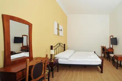 a bedroom with a bed and a mirror and a table at Penzion Královské lázně in Poděbrady