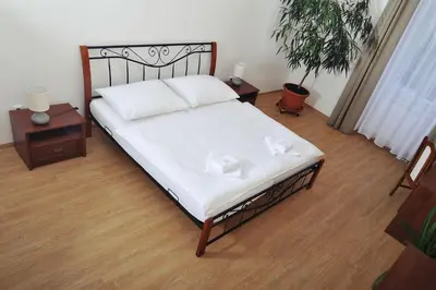 a bed in a room with two tables and a plant at Penzion Královské lázně in Poděbrady