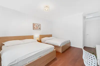 two beds in a room with white walls and wooden floors at The Dante Prague - Family Apartments with FREE PARKING in Prague