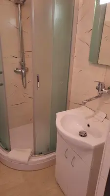 a white bathroom with a shower and a sink at Hotel U Beránků in Libochovice