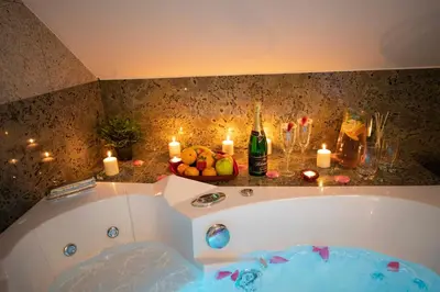 a bathroom with a tub with candles and a bottle of champagne at VIP suite hotel Heinz in Dobříš