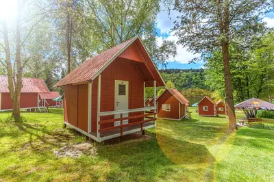 a small cabin in the middle of a field with trees at Kemp Andělská laguna Slapy in Nalžovice