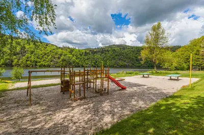 a playground with a slide and a bench in a park at Kemp Andělská laguna Slapy in Nalžovice