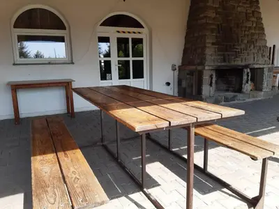 a wooden table and benches in front of a fireplace at Penzion Cerhenice in Cerhenice