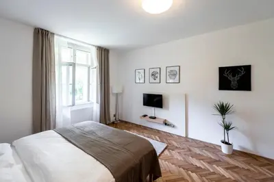 a white bedroom with a bed and a tv at Apartment Slavikova 11 in Prague