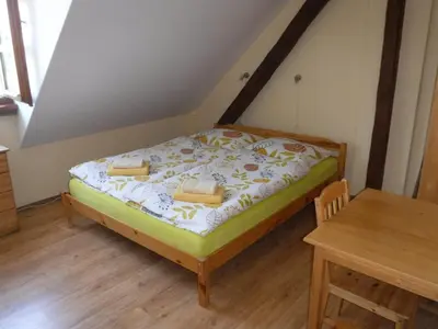 a small bed in a room with a wooden table at Farma Zahradnice in Olbramovice Ves