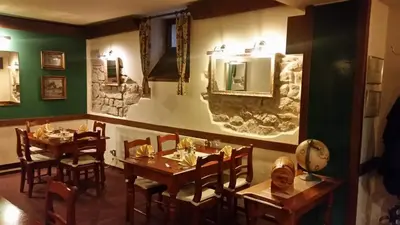 a restaurant with wooden tables and chairs and a stone wall at Penzion Pohoda Beroun in Beroun