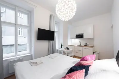 a white bedroom with a bed and a chandelier at Tesnov Residence Apartments in Prague