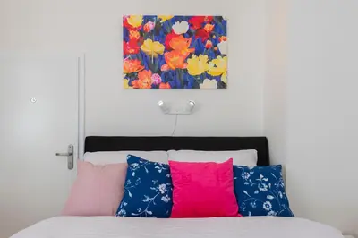 a bedroom with a bed with colorful pillows and a painting at Tesnov Residence Apartments in Prague