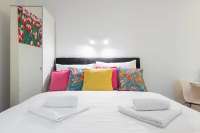 a bed with white sheets and colorful pillows at Tesnov Residence Apartments in Prague