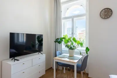 a living room with a table and a tv and a window at Tesnov Residence Apartments in Prague